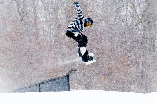 Snowboarder launches from a terrain park feature on a snowy day at Snow Creek