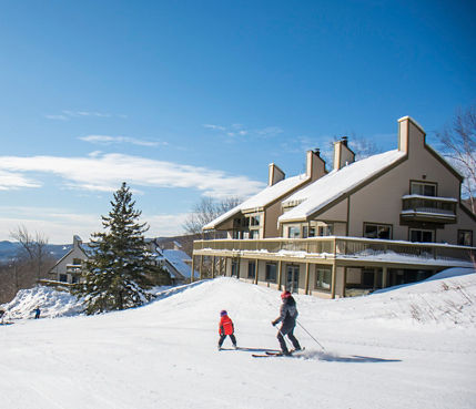 A parent and child ski near condos at Okemo