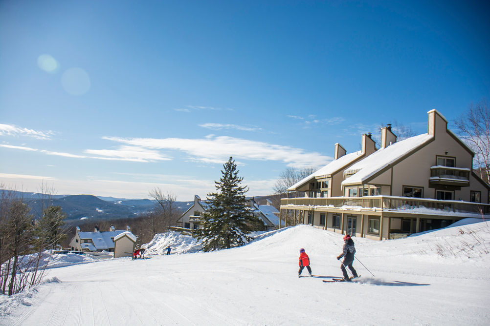 A parent and child ski near condos at Okemo