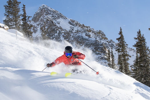 Skier making turn in fresh snow with Mount Crested Butte in the background