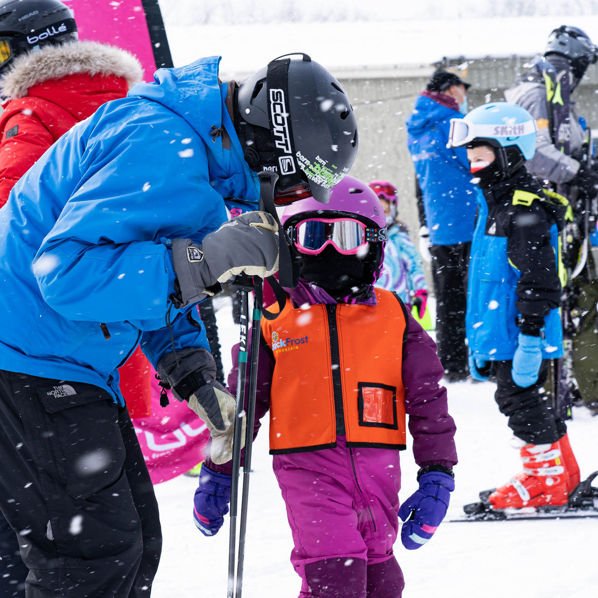 Female Ski instructor Helping Female Child Student get Skis on for Lesson at Jack Frost