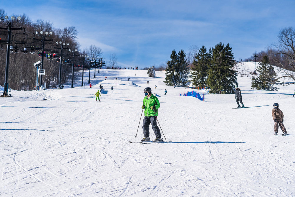 Guests skiing on a sunny day at Alpine Valley