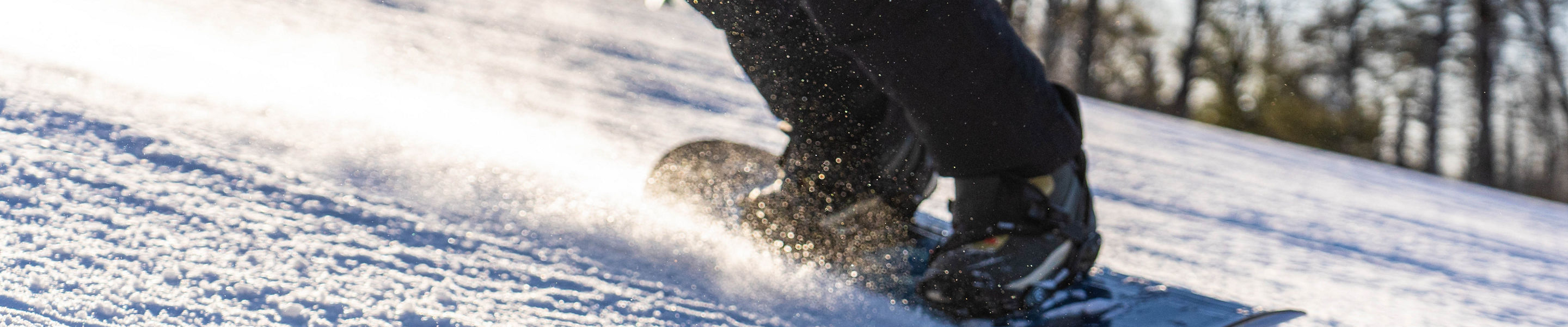 Snowboarder carving through corduroy snow with sunset glow at Big Boulder