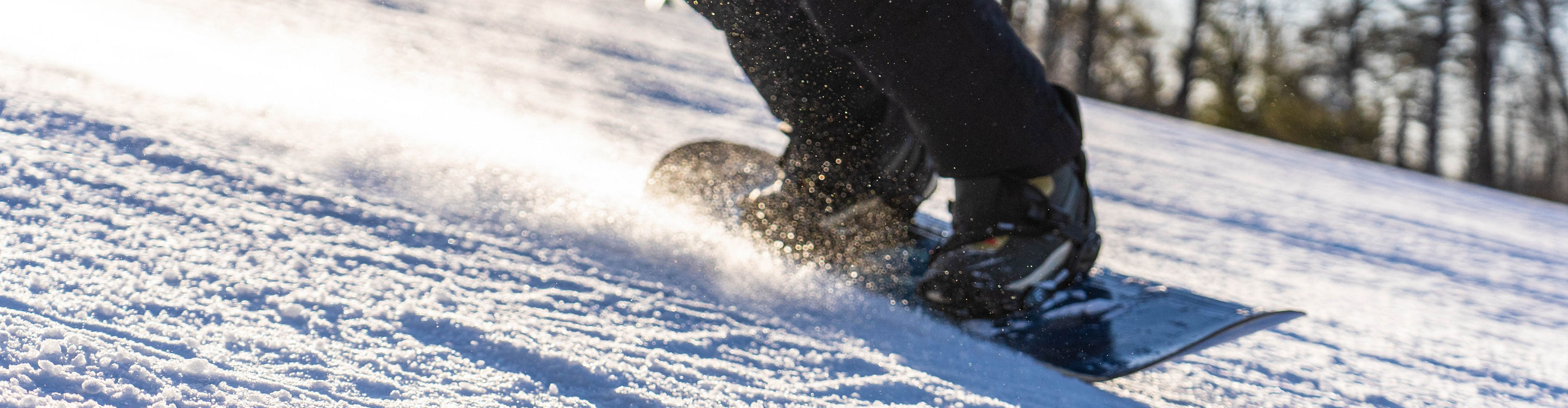 Snowboarder carving through corduroy snow with sunset glow at Big Boulder