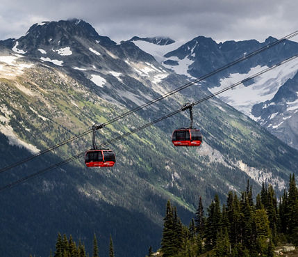 Scenic Shot of Gondolas at Whistler Blackcomb During Summer with Some Remaining Snow on the Mountaintops