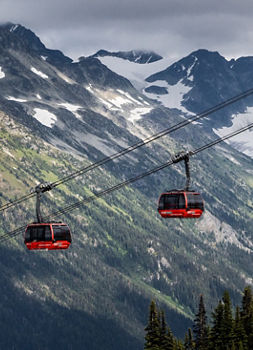 Scenic Shot of Gondolas at Whistler Blackcomb During Summer with Some Remaining Snow on the Mountaintops
