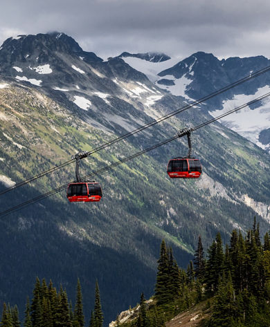 Scenic Shot of Gondolas at Whistler Blackcomb During Summer with Some Remaining Snow on the Mountaintops