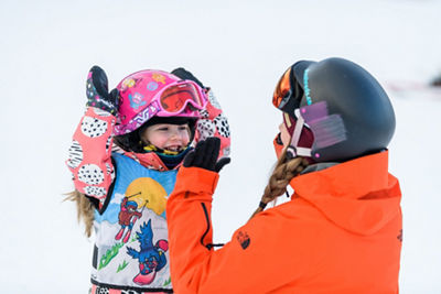 Young children snowboarding with instructor