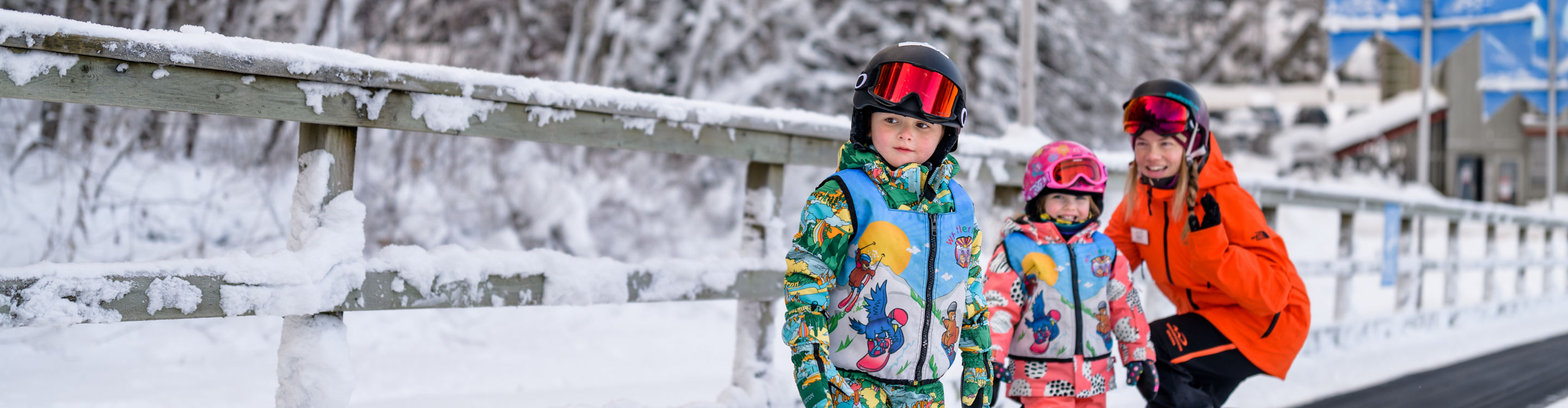 Young children snowboarding with instructor
