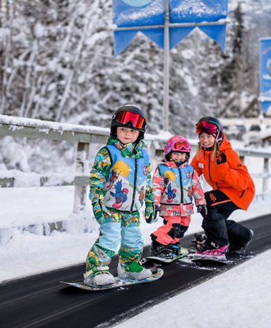 Young children snowboarding with instructor