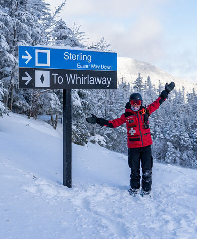 Ski Patroller Poses With Signage At Stowe Mountain Resort