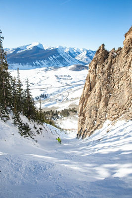 Skier making turns down Funnel with mountain background