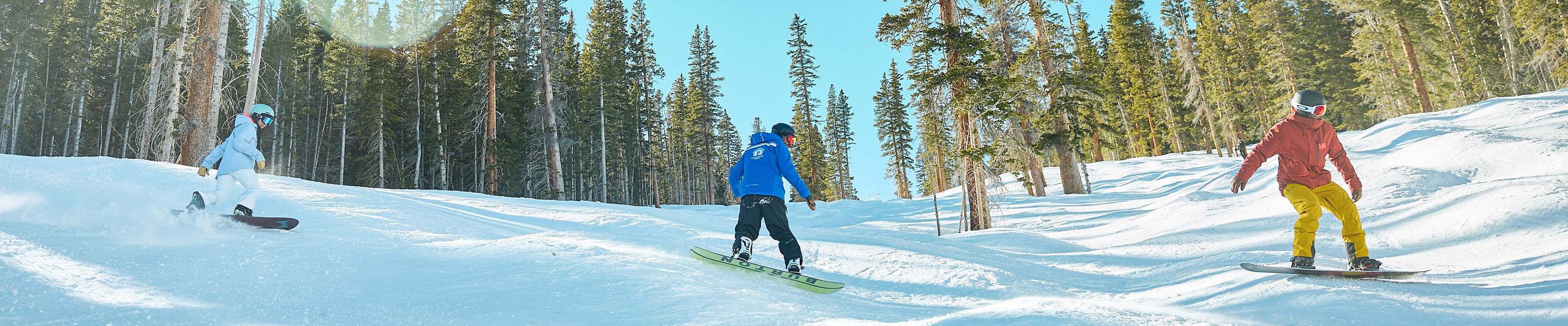 Adults snowboarding with an instructor