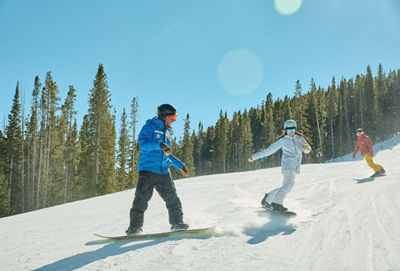 Adults snowboarding with an instructor