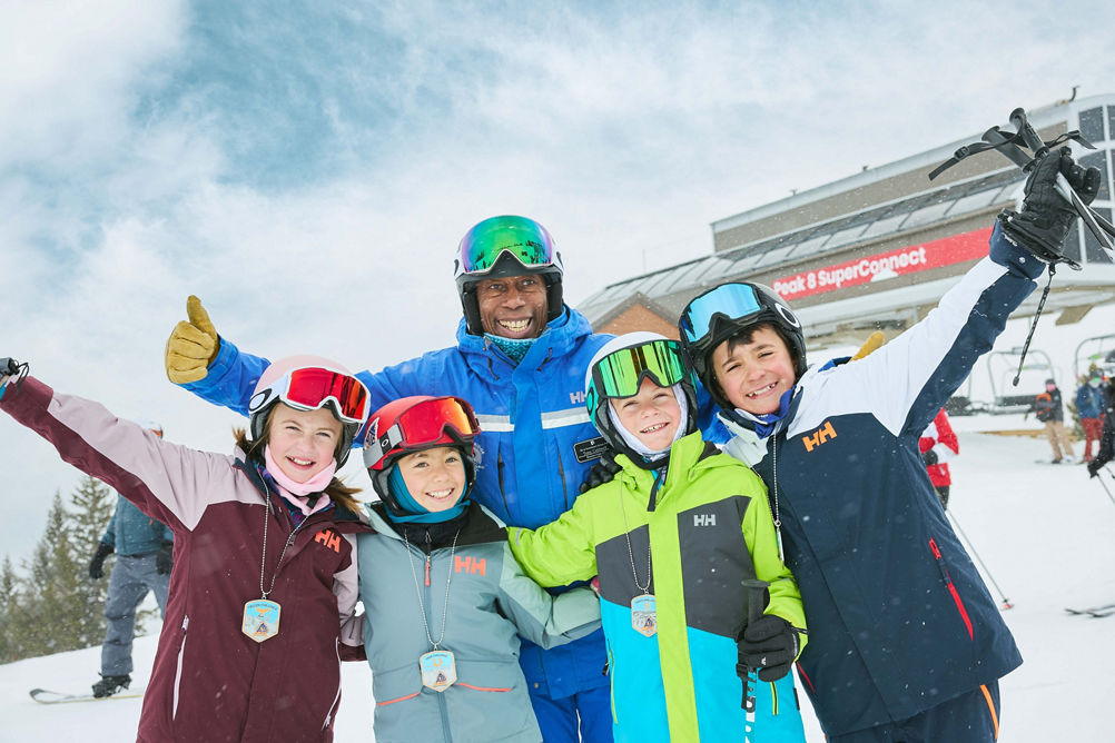 Older children skiing with an instructor (ATP)