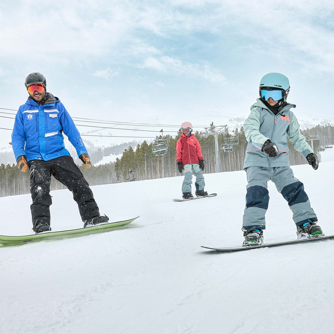 Older children snowboarding with an instructor (ATP)