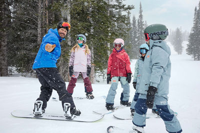 Older children snowboarding with an instructor (ATP)