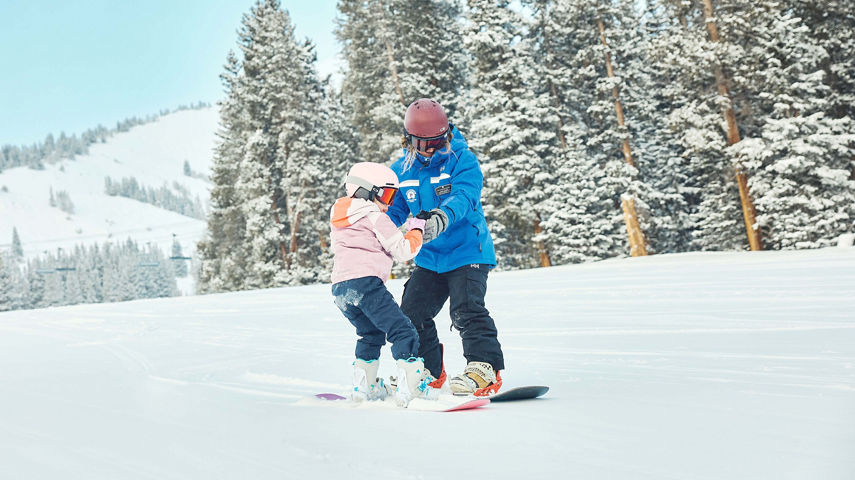 Young children snowboarding with an instructor