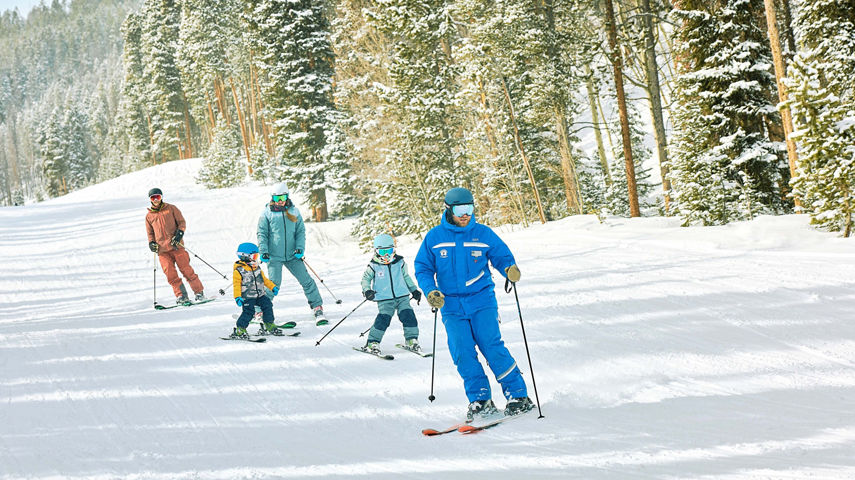 Family skiing with an instructor in a private lesson
