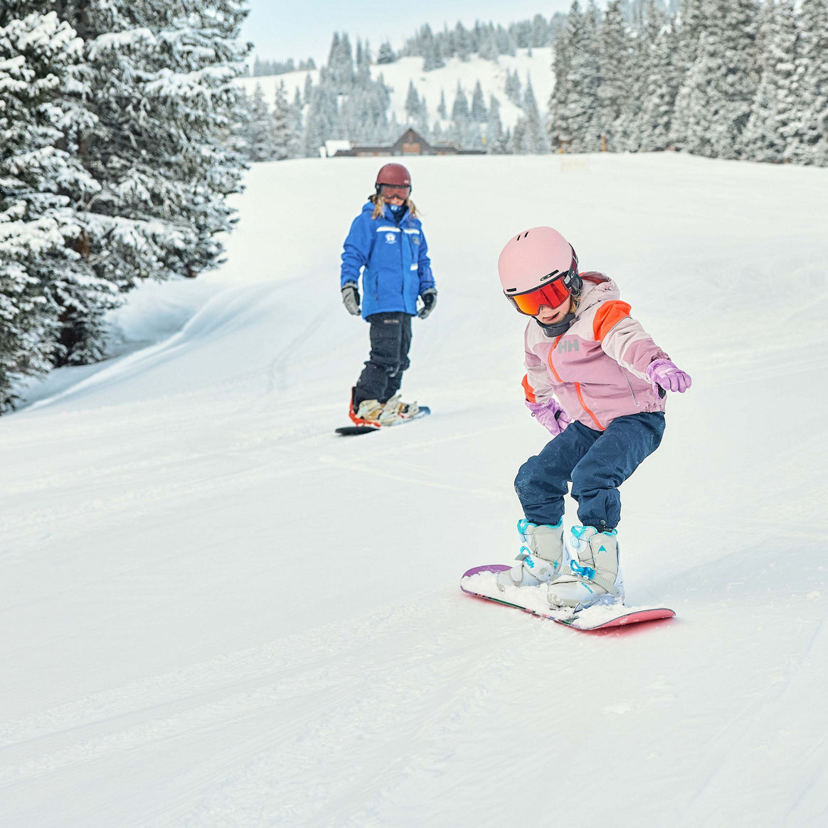 Young children snowboarding with an instructor