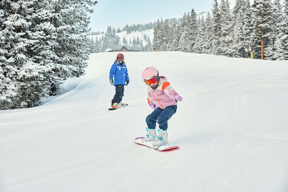 Young children snowboarding with an instructor