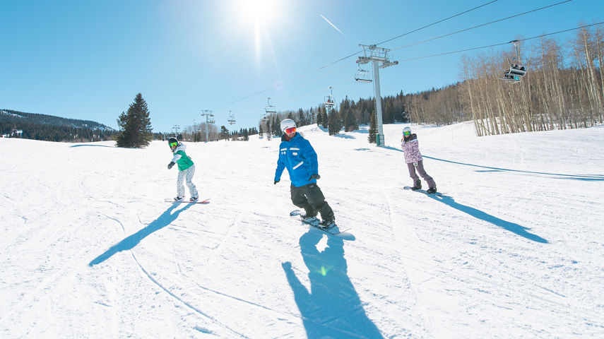 Adults snowboarding with an instructor