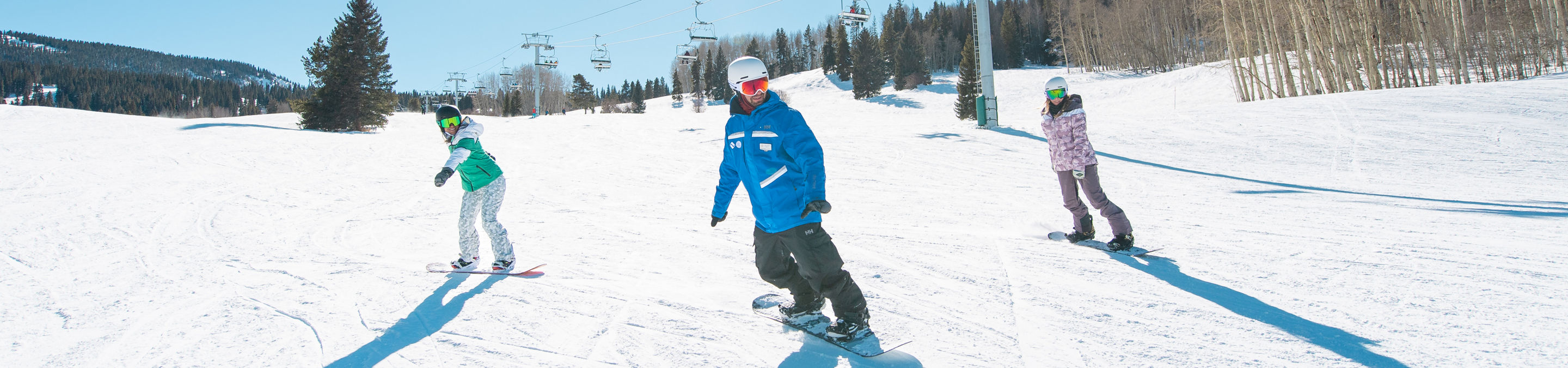 Adults snowboarding with an instructor