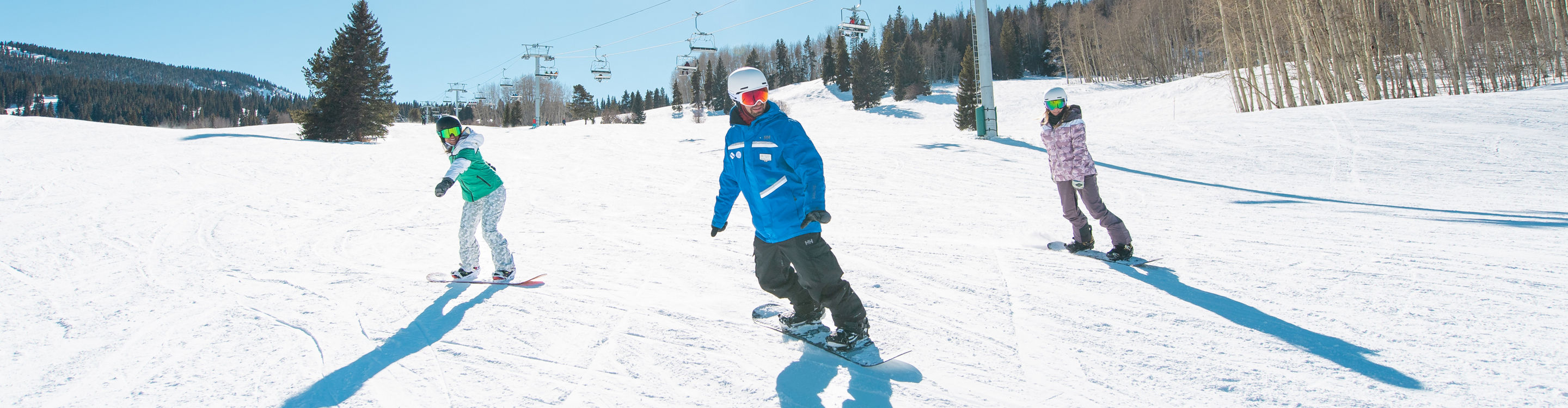 Adults snowboarding with an instructor
