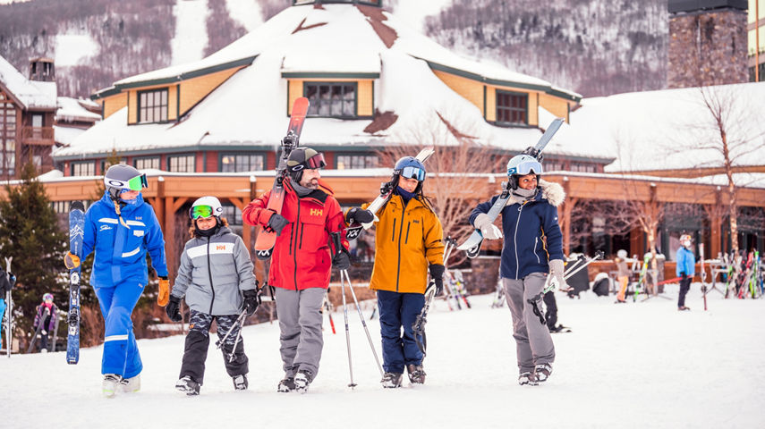 Family Walking Alongside Ski Instructor with Skis at the Stowe's Resort Base