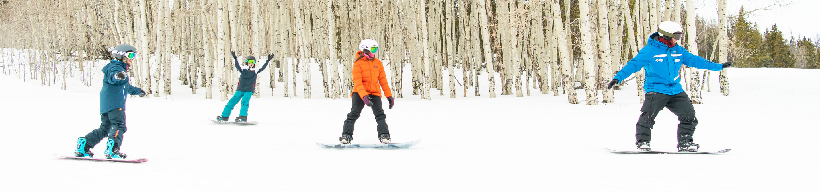 Older children snowboarding with an instructor