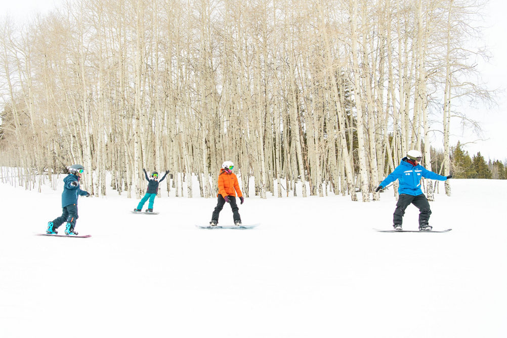 Older children snowboarding with an instructor