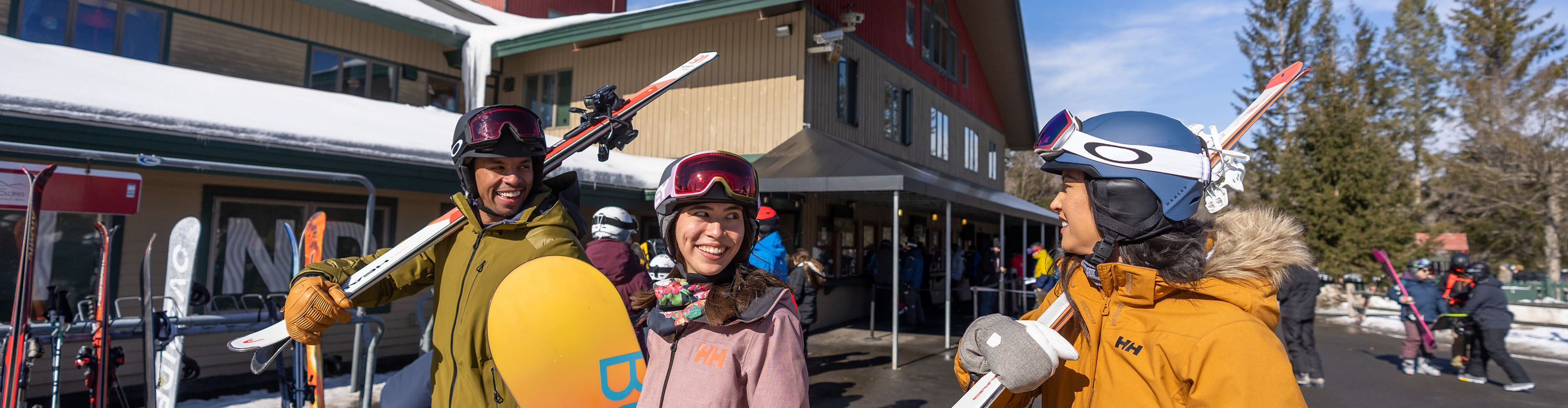Friends Carrying Equipment Walk on Main Street in front of Clocktower at Mount Snow