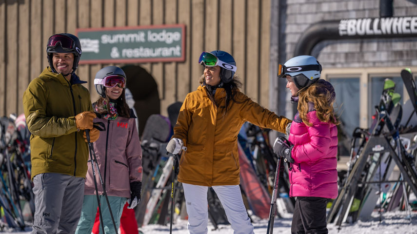 Friends Plan Trail in front of Summit Lodge and Bullwheel Sign at Mount Snow Summit