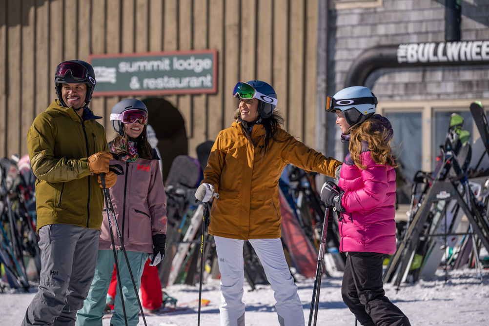 Friends Plan Trail in front of Summit Lodge and Bullwheel Sign at Mount Snow Summit