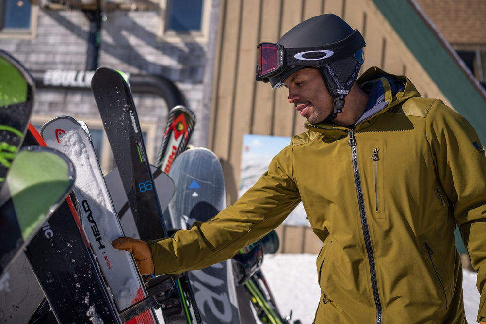 Man Grabs Skis from Rack at Summit of Mount Snow