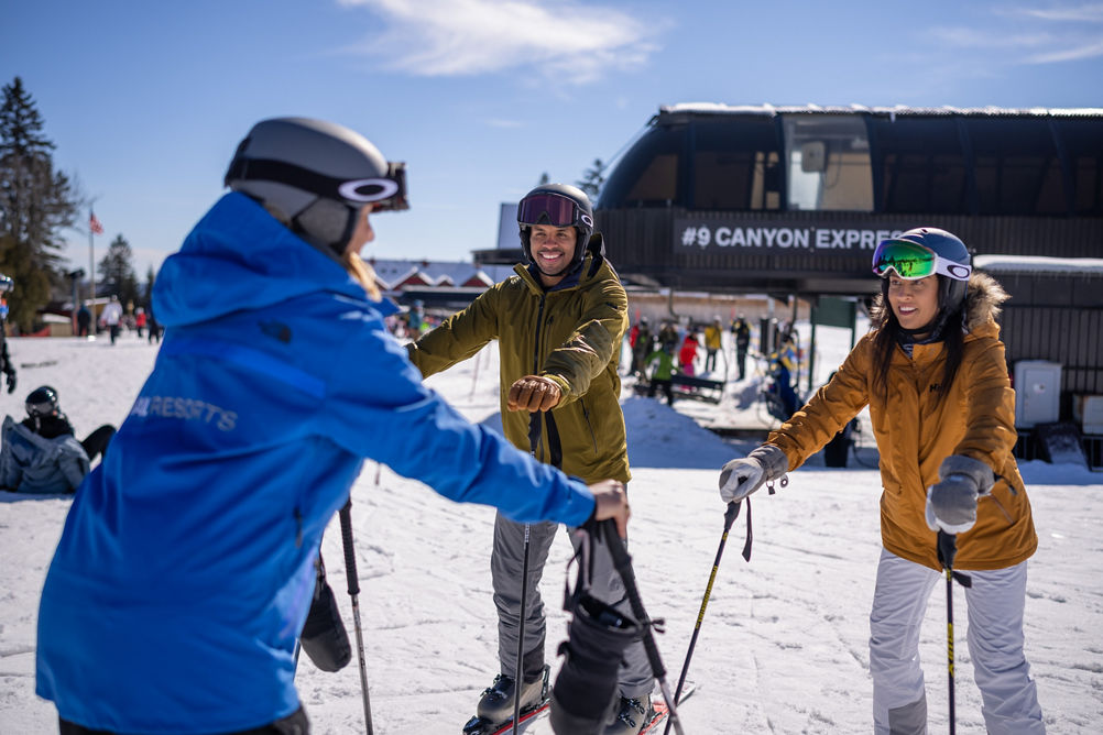 Skiers Smile at Ski & Ride School Instructor in front of Canyon Express Terminal at Mount Snow
