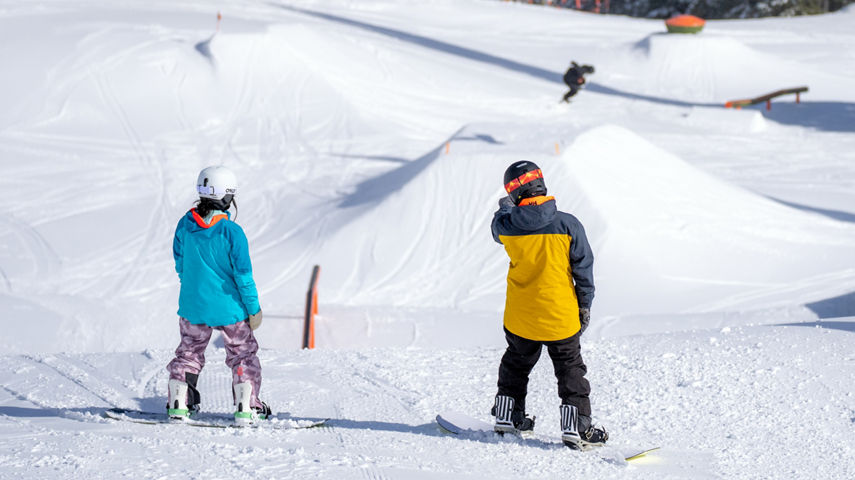 Two Snowboarders Examine a Ramp at the Terrain Park at Stevens Pass