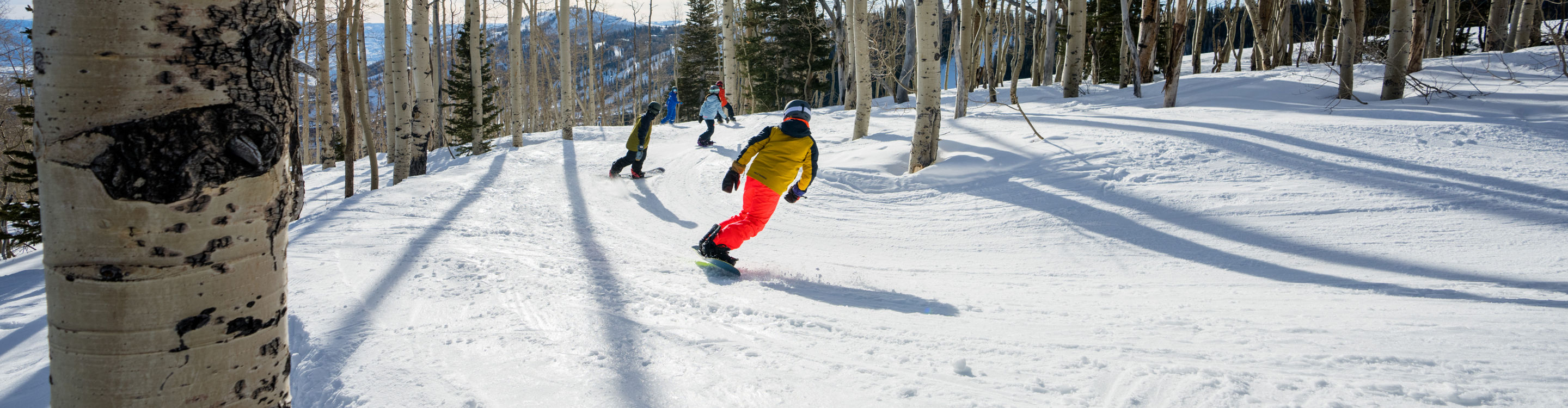 Older children snowboarding with an instructor (ATP)