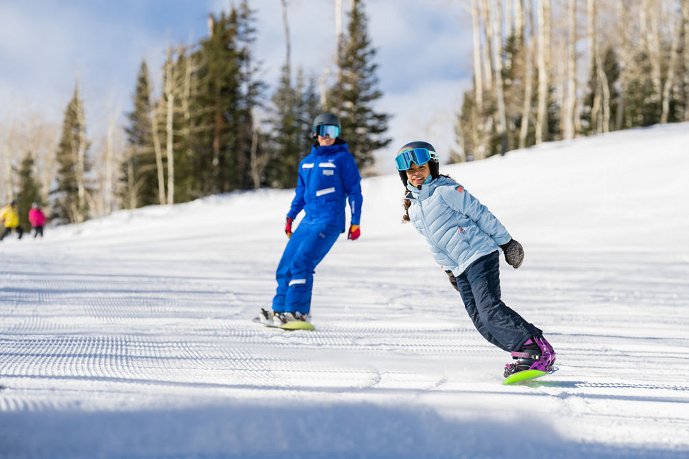 Older children snowboarding with an instructor (ATP)