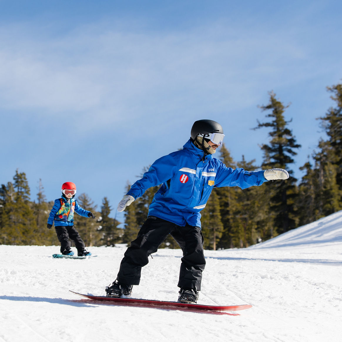 Young children snowboarding with an instructor