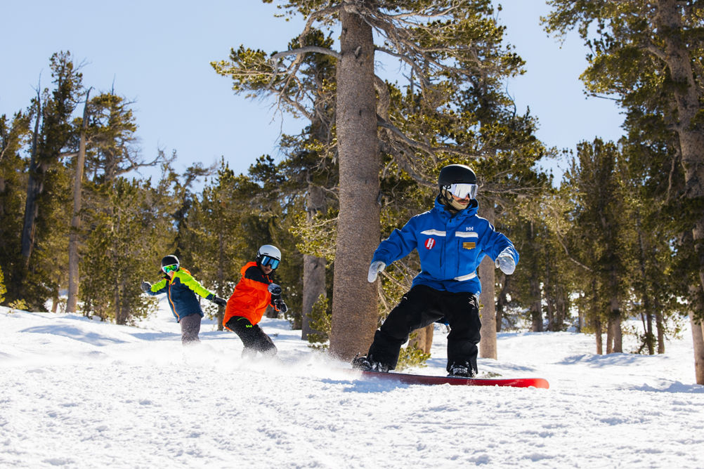 Older children snowboarding with an instructor