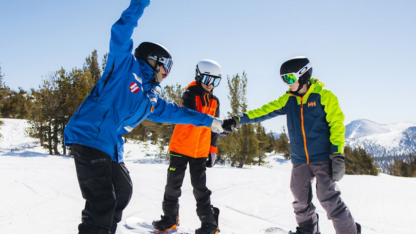 Older children snowboarding with an instructor