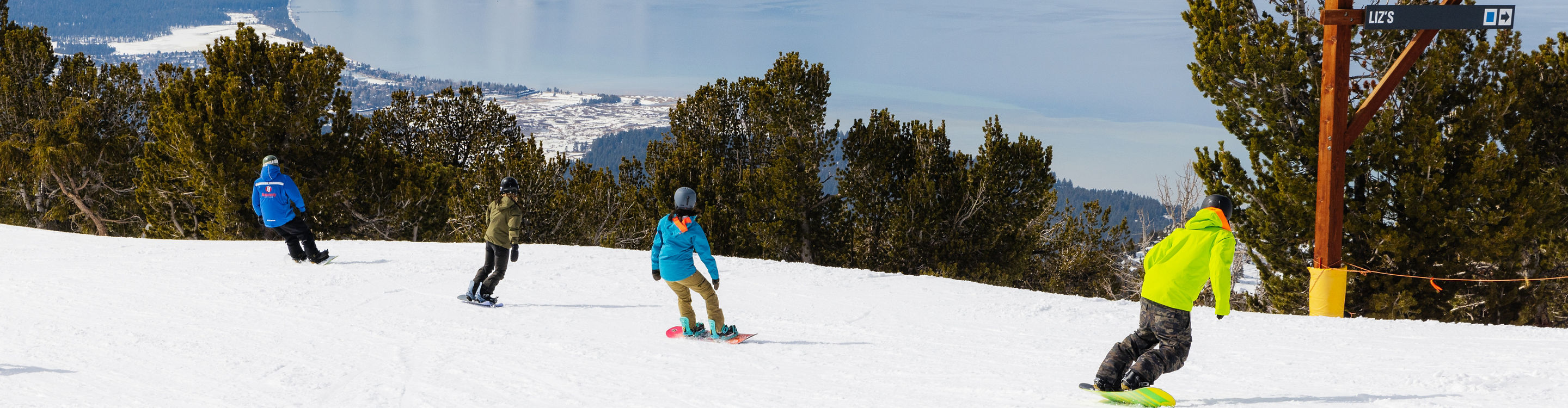 Adults snowboarding with an instructor