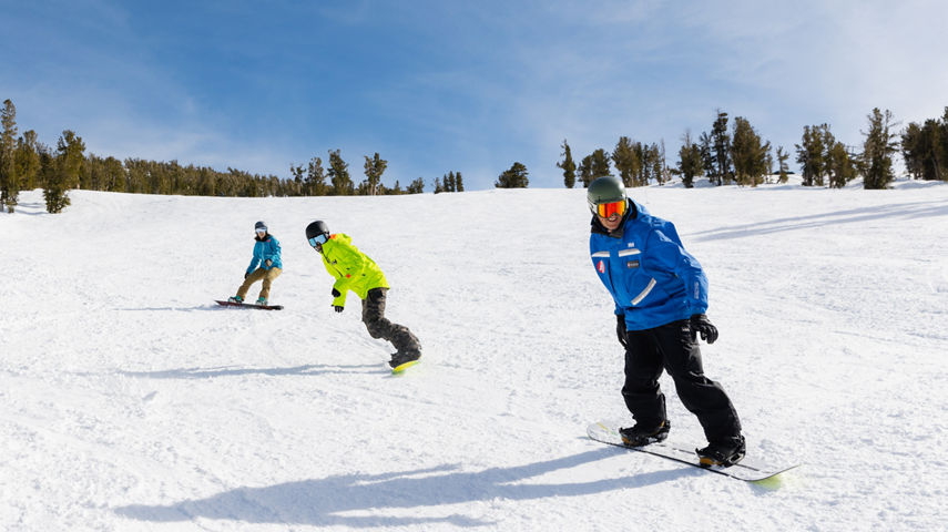 Adults snowboarding with an instructor