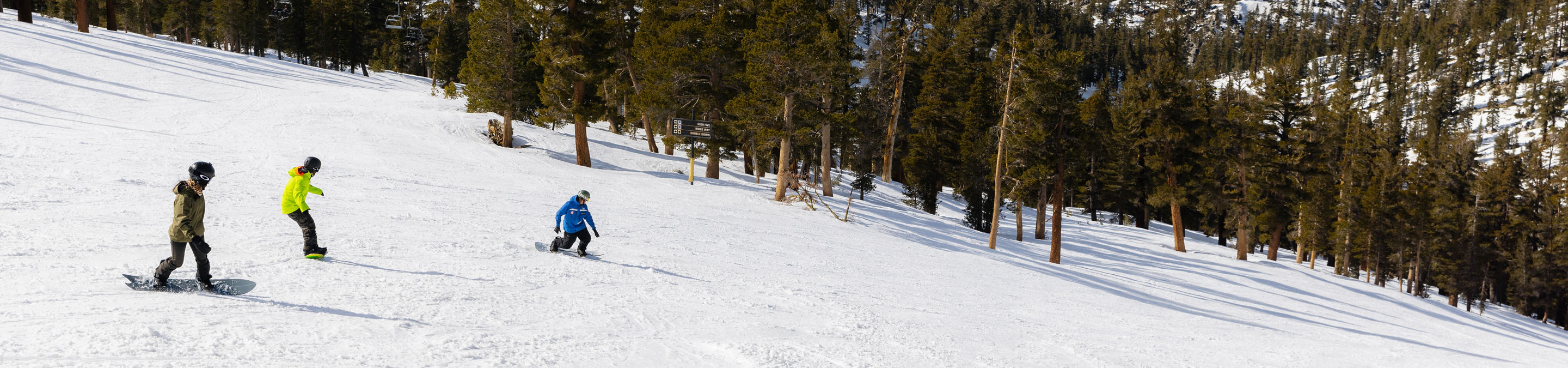 Adults snowboarding with an instructor