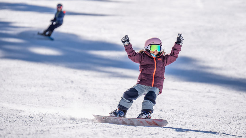 Older children snowboarding with an instructor