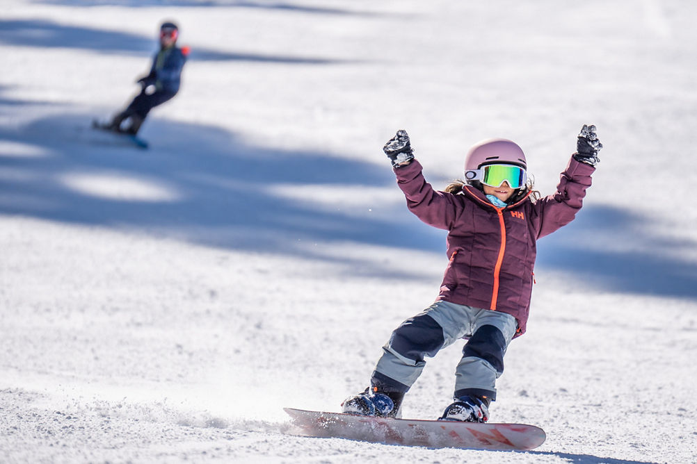 Older children snowboarding with an instructor