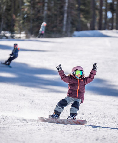 Older children snowboarding with an instructor