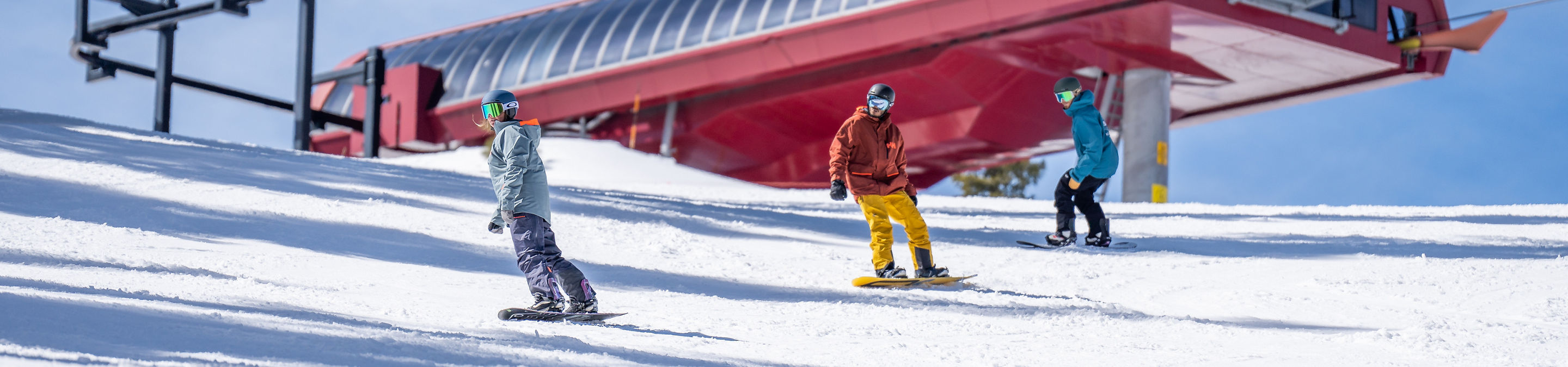 Adults snowboarding with an instructor