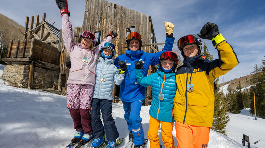 Older children skiing with an instructor (ATP)